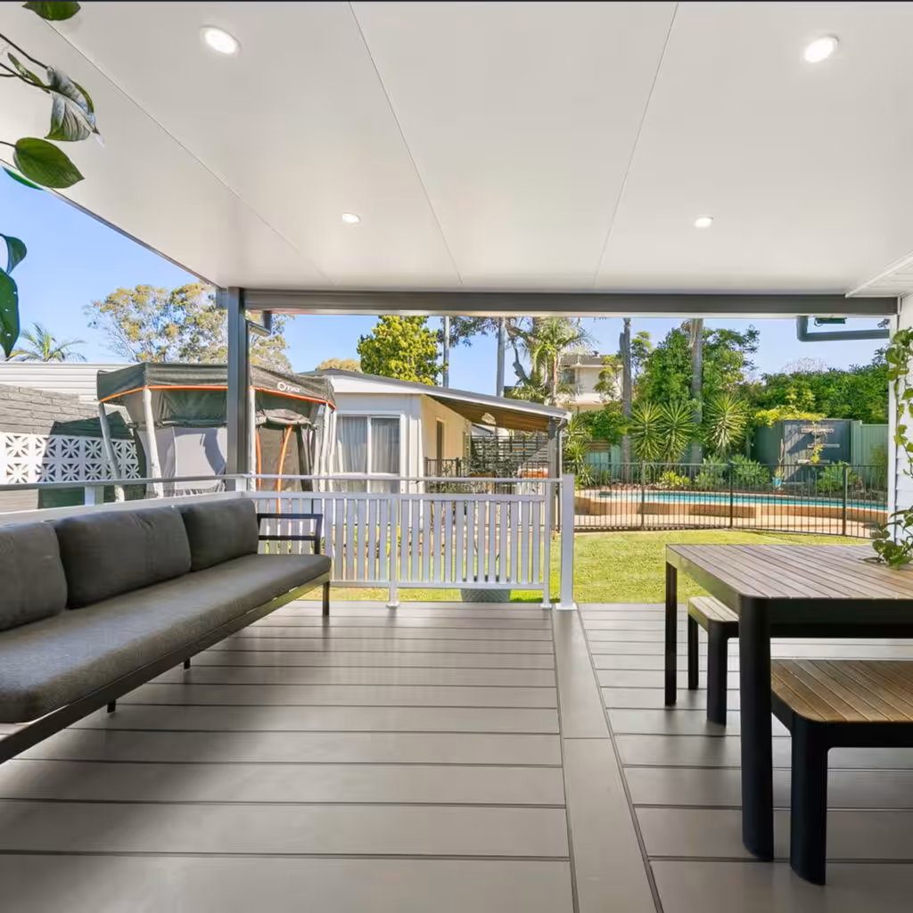 DIY attached flat roof patio with seating overlooking a green garden.