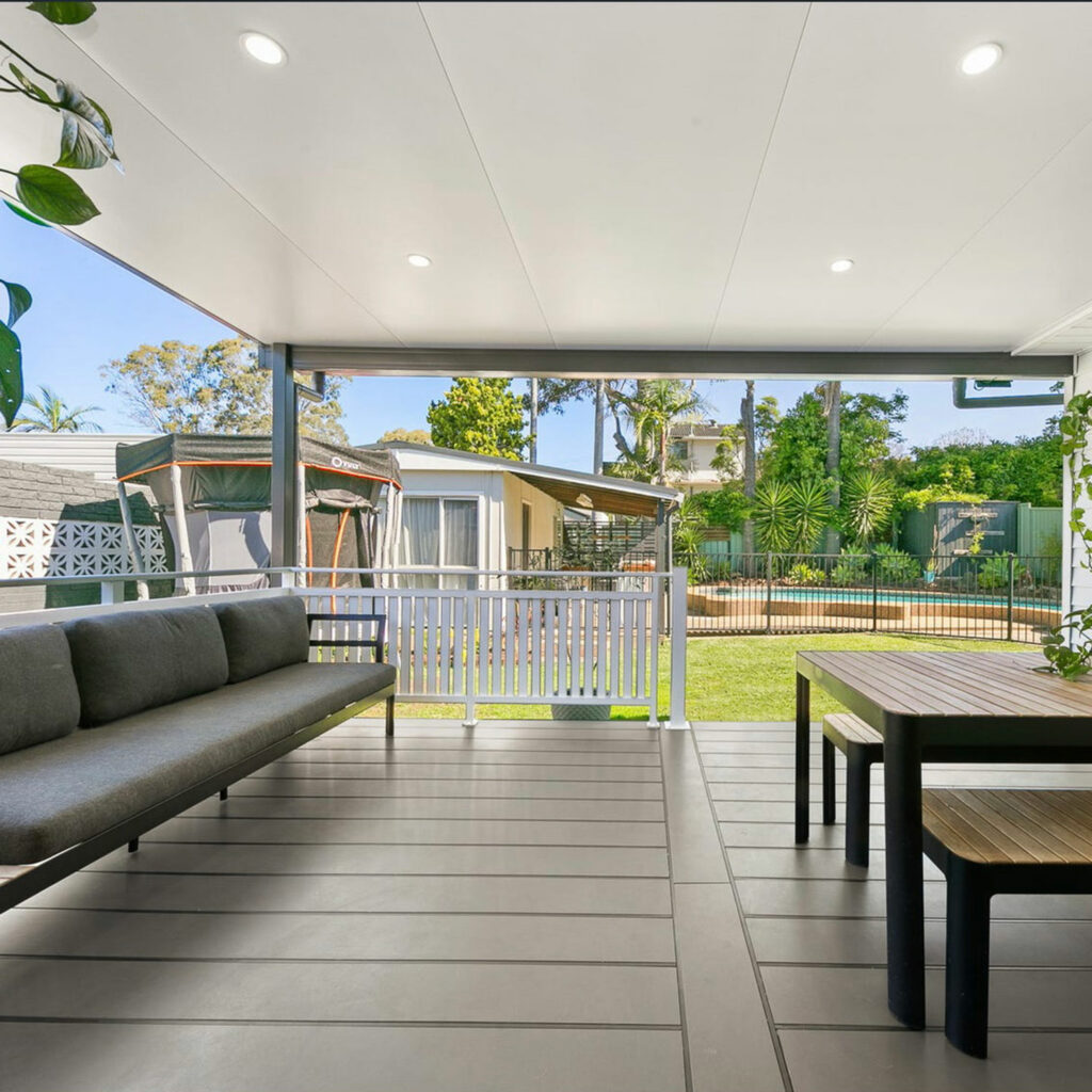 DIY attached flat roof patio with seating overlooking a green garden.