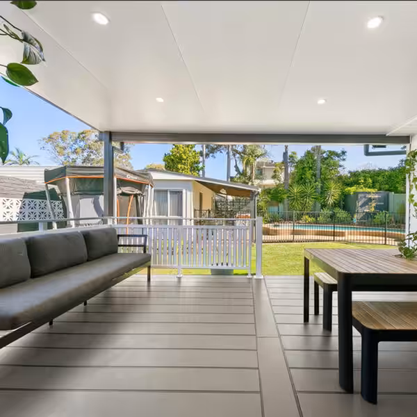 DIY attached flat roof patio with seating overlooking a green garden.
