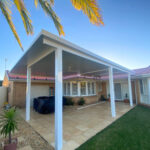 DIY attached flyover flat roof patio/pergola kits with white posts and outdoor furniture.