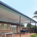 DIY attached flyover flat roof patio/pergola area with roof and outdoor furniture.