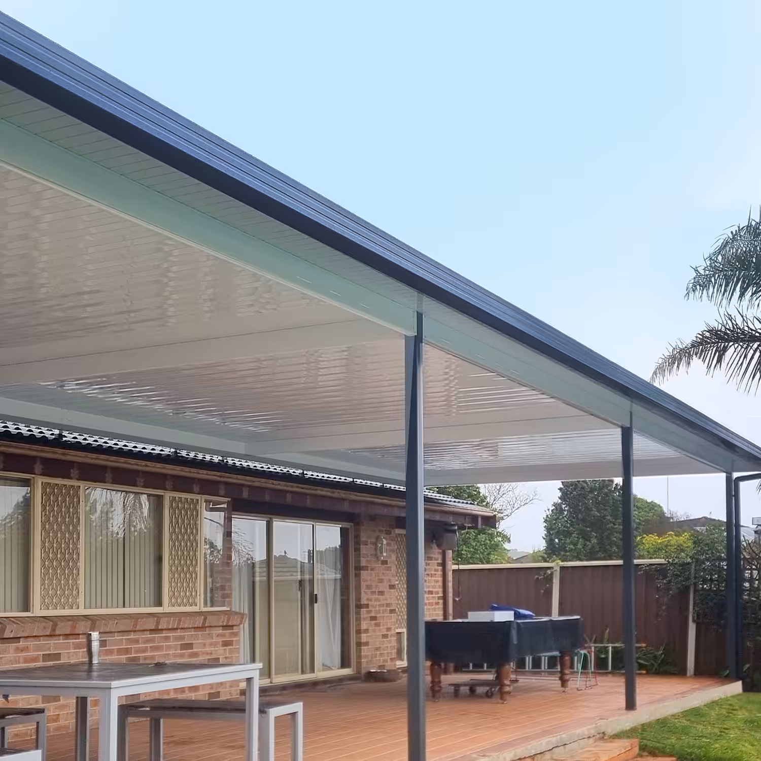 DIY attached flyover flat roof patio/pergola area with roof and outdoor furniture.