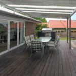 DIY attached flyover flat roof patio/pergola with barbecue and seating.