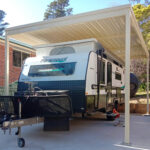 Caravan parked under a diy freestanding flat roof carport