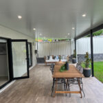 DIY attached flat roof pergola/patio with dining table and seating.