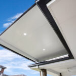 DIY attached flyover flat roof patio/pergola with downlights against blue sky.