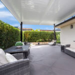 DIY attached flyover flat roof patio/pergola with seating and greenery.