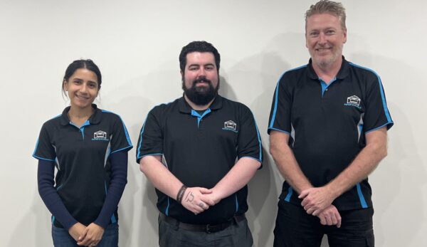 Three team members posing together, wearing uniforms.